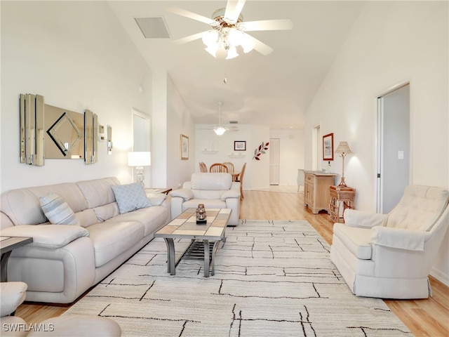 living room featuring light hardwood / wood-style floors, high vaulted ceiling, and ceiling fan