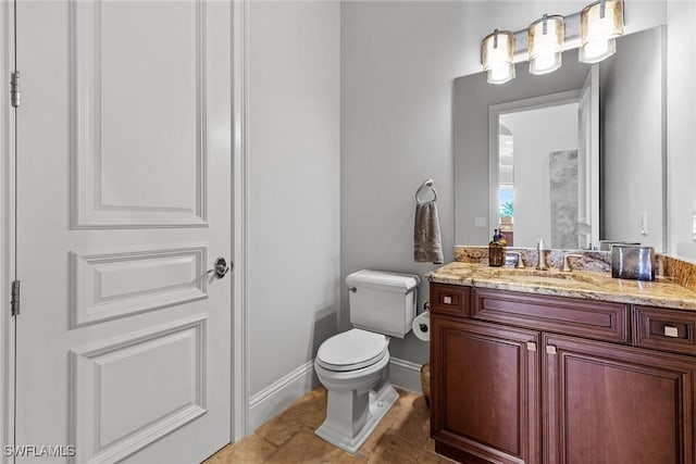 bathroom with tile patterned flooring, baseboards, vanity, and toilet