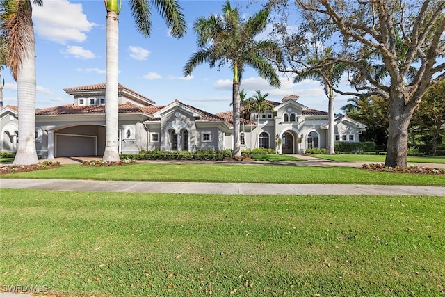 mediterranean / spanish home featuring a garage and a front yard