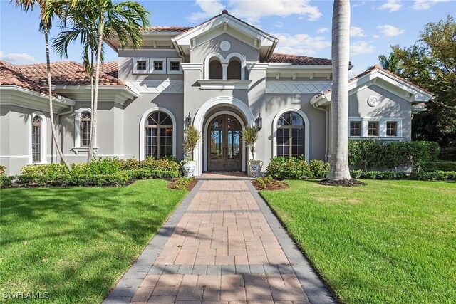 mediterranean / spanish-style house with a front yard and french doors