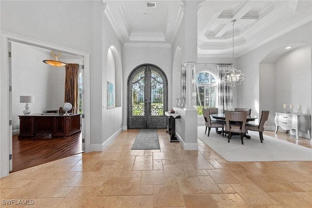 entrance foyer with a towering ceiling, stone tile floors, baseboards, and arched walkways