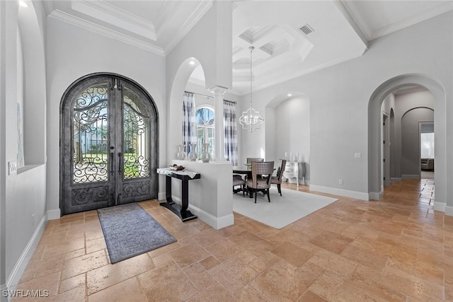 entrance foyer with arched walkways, crown molding, stone tile flooring, visible vents, and baseboards