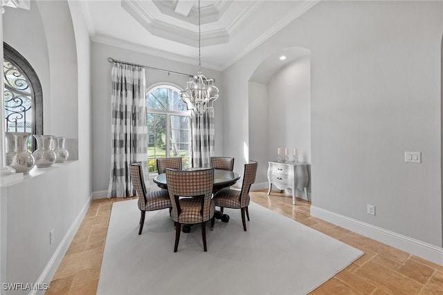 dining room with a chandelier, arched walkways, baseboards, a tray ceiling, and crown molding