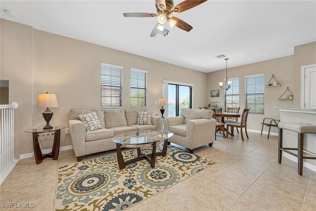 tiled living room with a healthy amount of sunlight and ceiling fan with notable chandelier