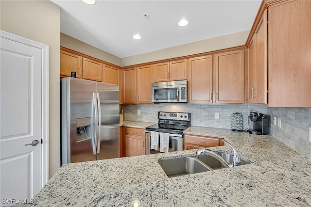 kitchen with light stone counters, stainless steel appliances, and sink