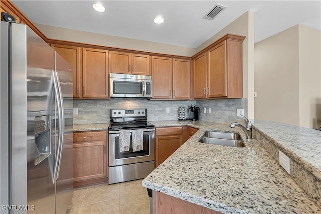 kitchen featuring decorative backsplash, stainless steel appliances, sink, light stone countertops, and light tile patterned floors