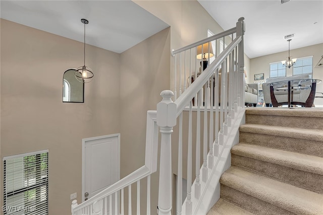 staircase with an inviting chandelier