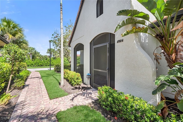 view of exterior entry featuring a lawn