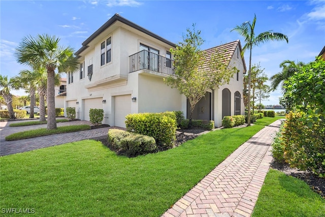 view of front facade featuring a front yard, a balcony, and a garage