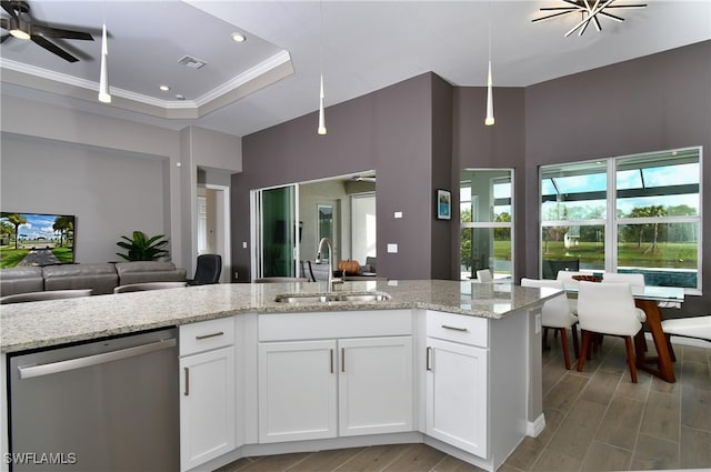 kitchen with sink, stainless steel dishwasher, light stone countertops, decorative light fixtures, and white cabinetry