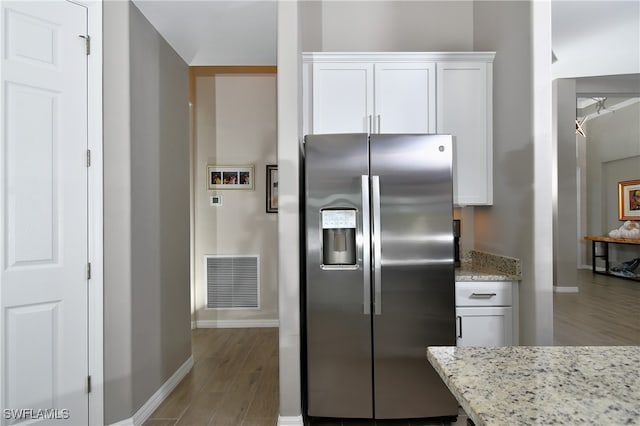 kitchen featuring stainless steel refrigerator with ice dispenser, light stone countertops, white cabinets, and light wood-type flooring