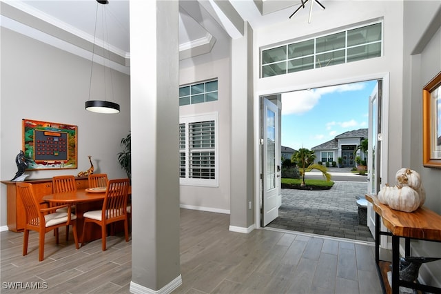 entryway with crown molding, breakfast area, a towering ceiling, and wood-type flooring