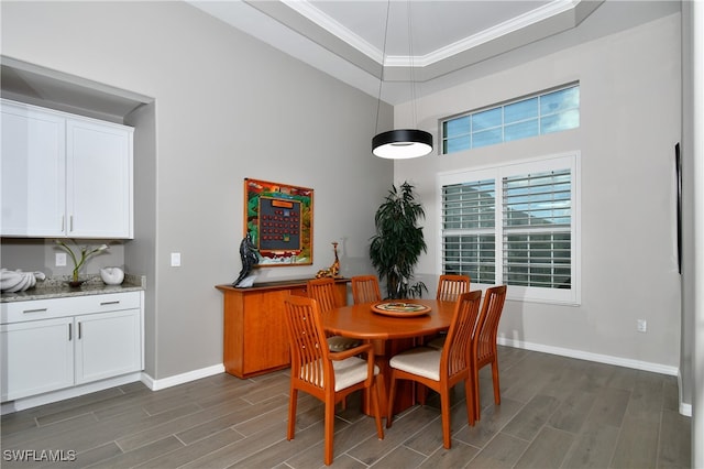 dining room with dark hardwood / wood-style floors, a tray ceiling, and ornamental molding