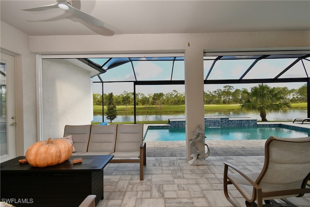 view of swimming pool with a lanai, ceiling fan, a hot tub, a water view, and a patio area