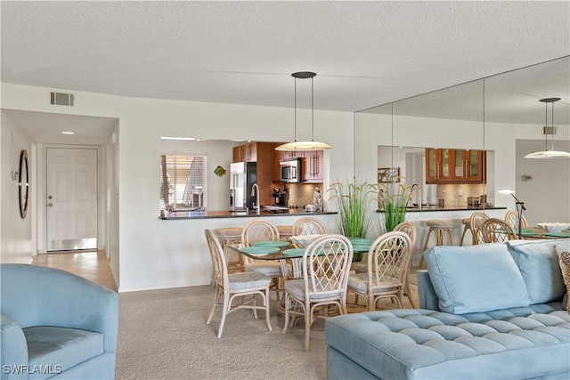 dining space with a textured ceiling and light carpet