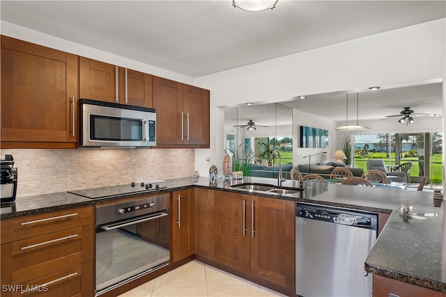 kitchen with dark stone countertops, light tile patterned floors, sink, and appliances with stainless steel finishes