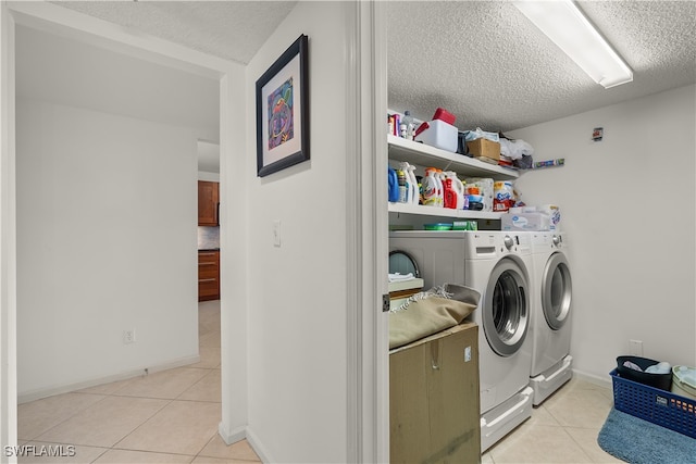 washroom with light tile patterned floors, a textured ceiling, and independent washer and dryer