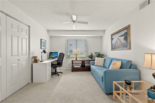 carpeted home office with ceiling fan and a textured ceiling