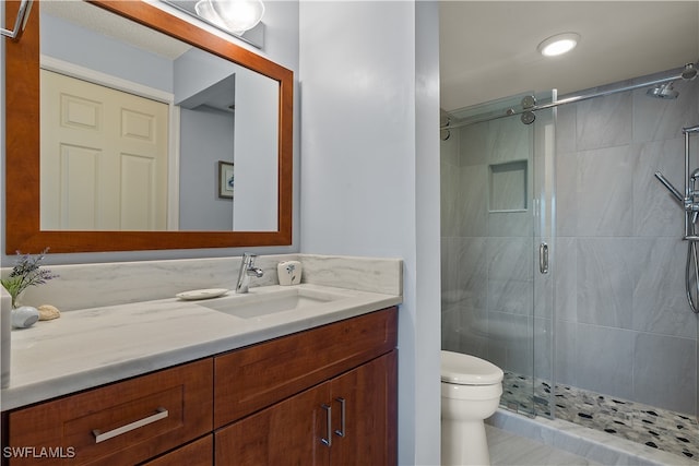 bathroom with tile patterned floors, vanity, a shower with shower door, and toilet