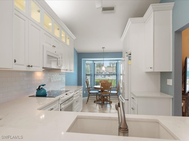 kitchen with light stone countertops, white cabinetry, sink, decorative light fixtures, and white appliances