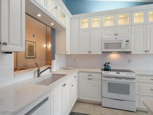 kitchen with white appliances, backsplash, white cabinets, sink, and light tile patterned floors