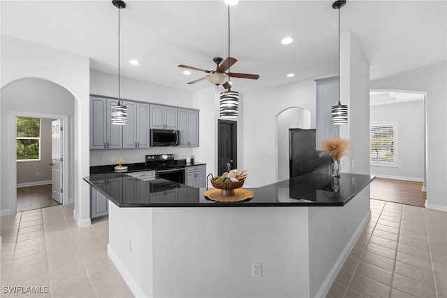 3645 70th Ave NE, Naples, FL 34120 - kitchen featuring stainless steel appliances, arched walkways, dark countertops, gray cabinetry, and light tile patterned floors