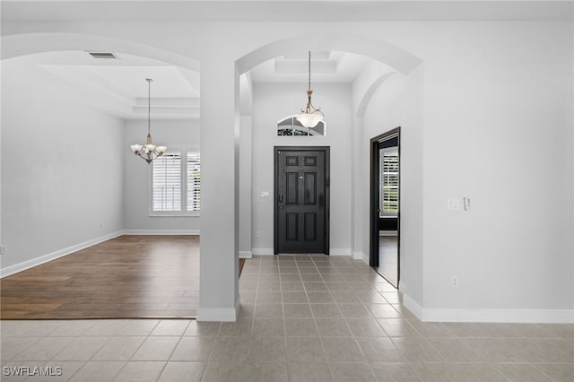 entryway with a chandelier, a tray ceiling, and light hardwood / wood-style flooring