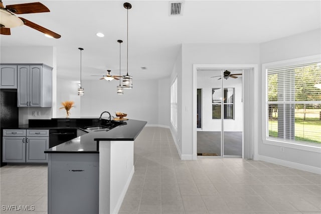 kitchen with light tile patterned floors, gray cabinets, hanging light fixtures, sink, and dishwasher