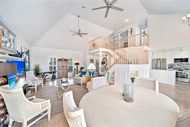 dining room with ceiling fan, high vaulted ceiling, and light hardwood / wood-style floors