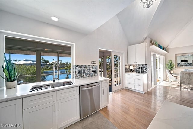 kitchen with sink, white cabinetry, a water view, decorative backsplash, and stainless steel dishwasher