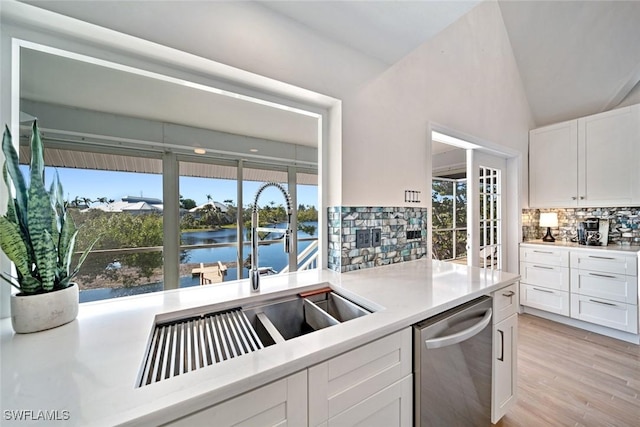 kitchen with a wealth of natural light, stainless steel dishwasher, white cabinets, and a water view