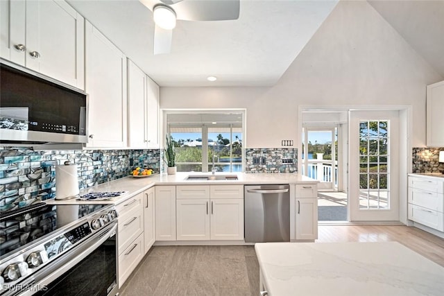 kitchen featuring lofted ceiling, sink, white cabinetry, appliances with stainless steel finishes, and ceiling fan