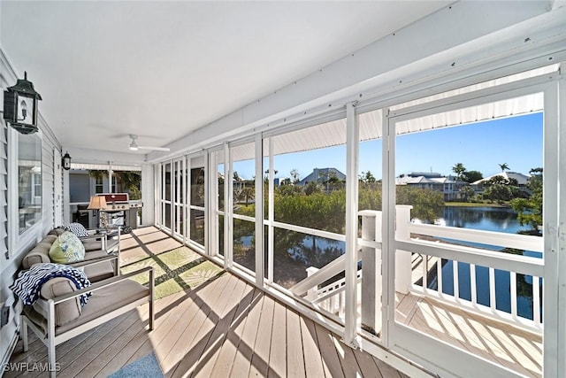 sunroom with a water view and ceiling fan