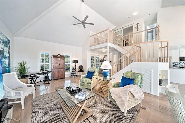 living room featuring ceiling fan, high vaulted ceiling, and light hardwood / wood-style floors