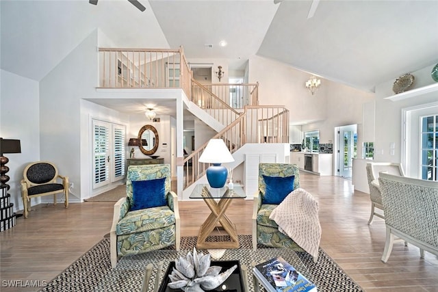 interior space featuring hardwood / wood-style flooring, ceiling fan with notable chandelier, and a high ceiling