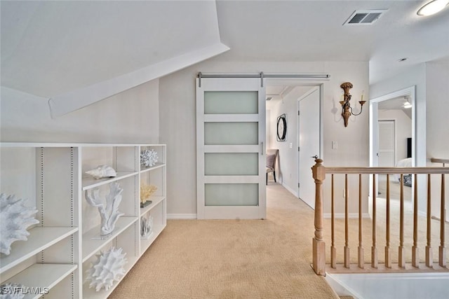 corridor featuring vaulted ceiling, a barn door, and light colored carpet