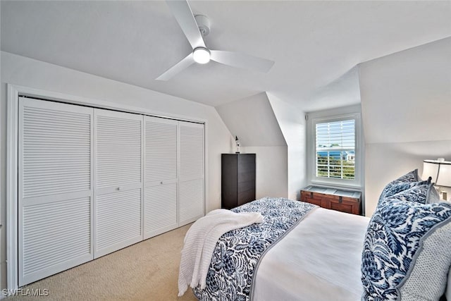 bedroom featuring vaulted ceiling, light carpet, ceiling fan, and a closet