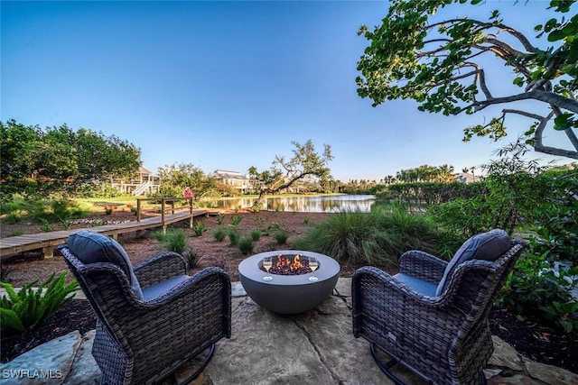 view of patio with a fire pit and a water view