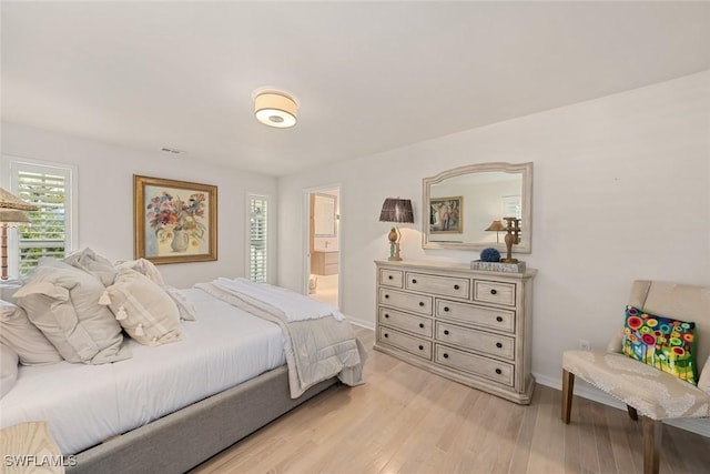 bedroom with light wood-type flooring and ensuite bath