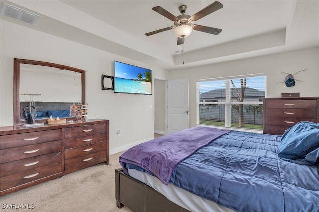 bedroom with ceiling fan, a raised ceiling, and light colored carpet