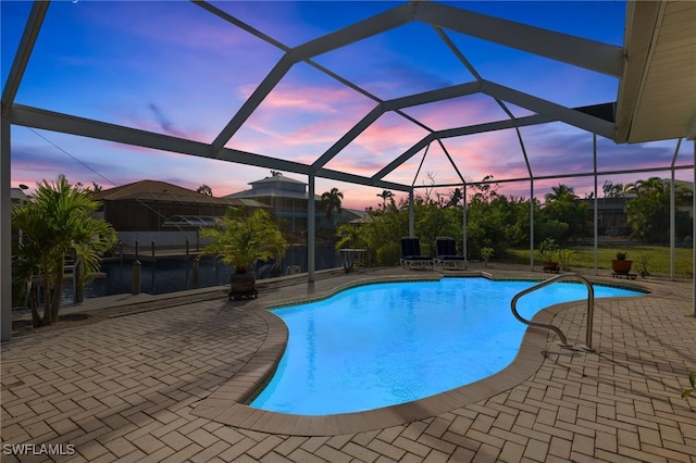 pool at dusk with a patio and glass enclosure