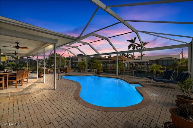 pool at dusk with a lanai and a patio