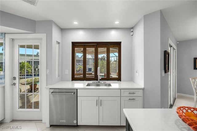 kitchen with white cabinets, sink, light tile patterned floors, and stainless steel dishwasher