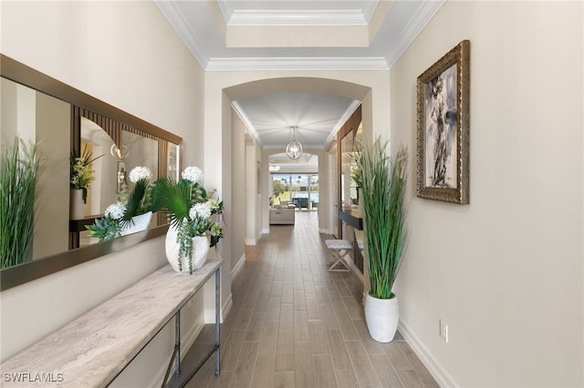 hall featuring hardwood / wood-style floors, crown molding, and a tray ceiling