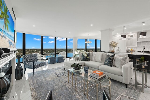 living room with a chandelier, a wall of windows, plenty of natural light, and sink