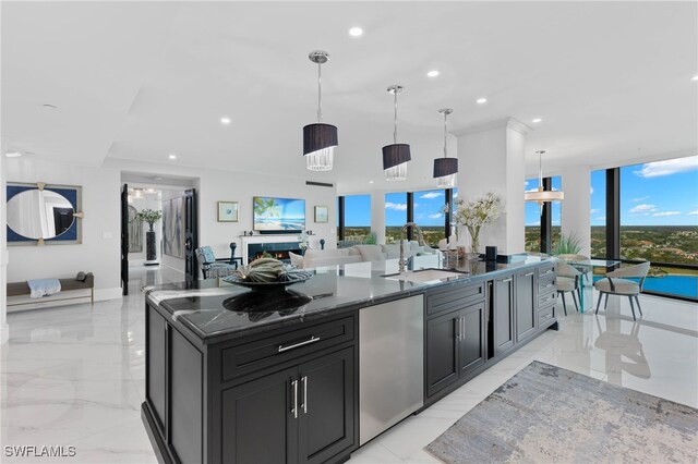 kitchen featuring a wealth of natural light, a large island, sink, pendant lighting, and fridge