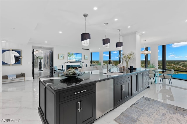 kitchen featuring decorative light fixtures, sink, stainless steel fridge, a large island, and plenty of natural light