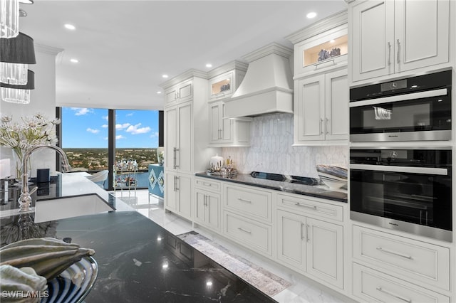 kitchen featuring white cabinets, sink, premium range hood, and black double oven