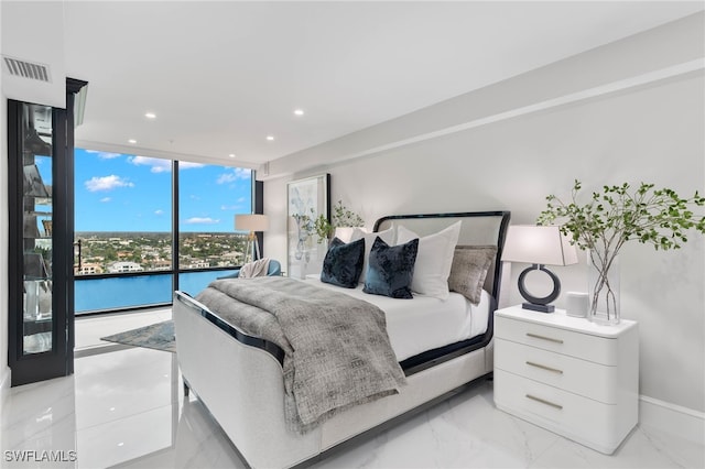 bedroom with floor to ceiling windows, access to exterior, and a water view