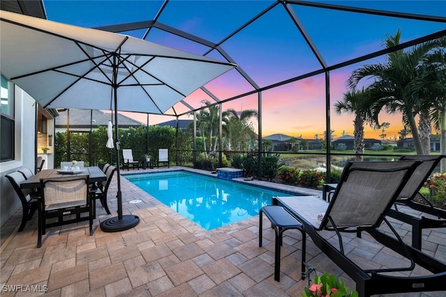 pool at dusk featuring a lanai, a water view, and a patio